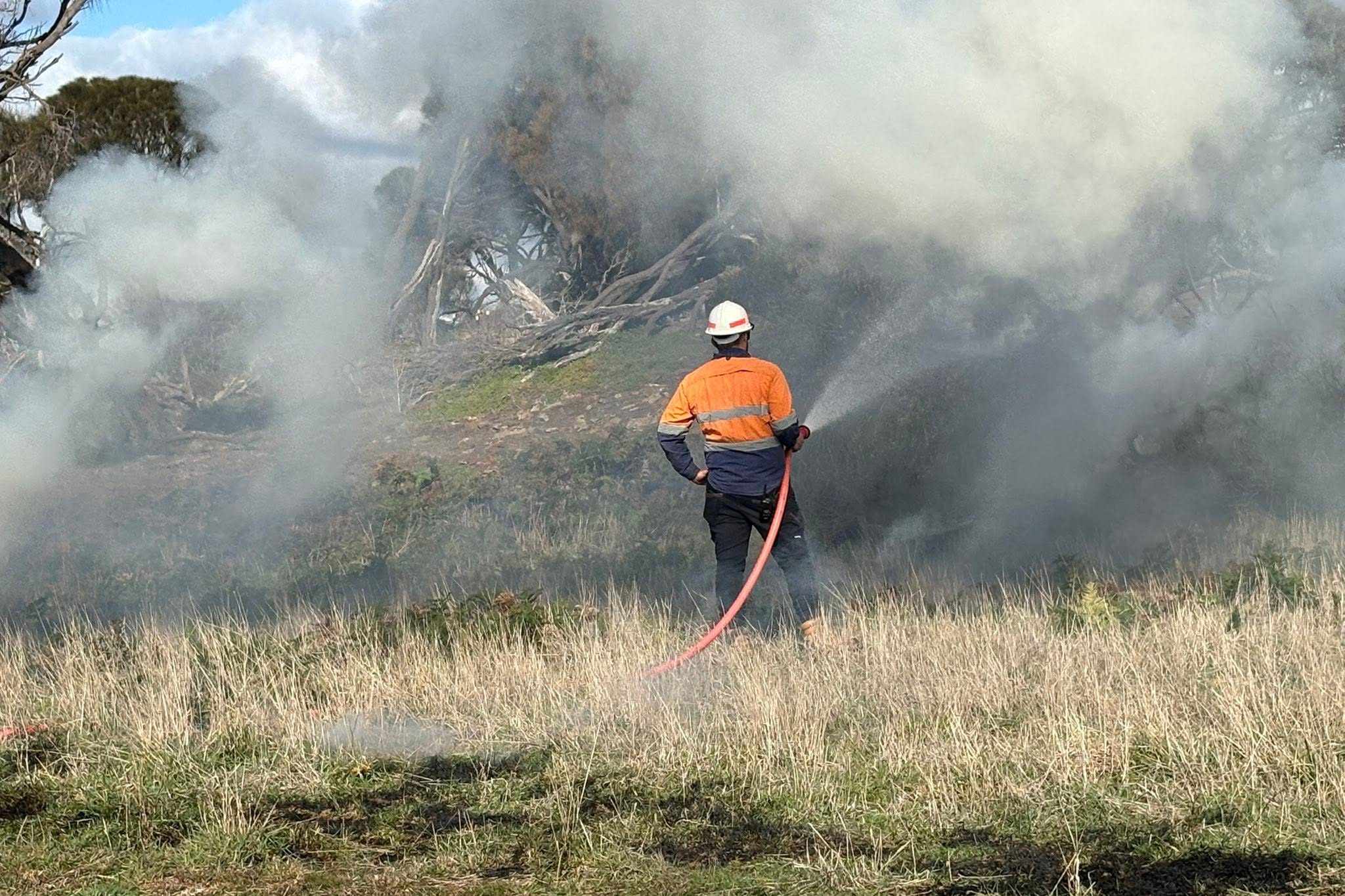 CULTURAL BURNING HOSE Aboriginal ranger with fire hose conducting cultural burning for land management