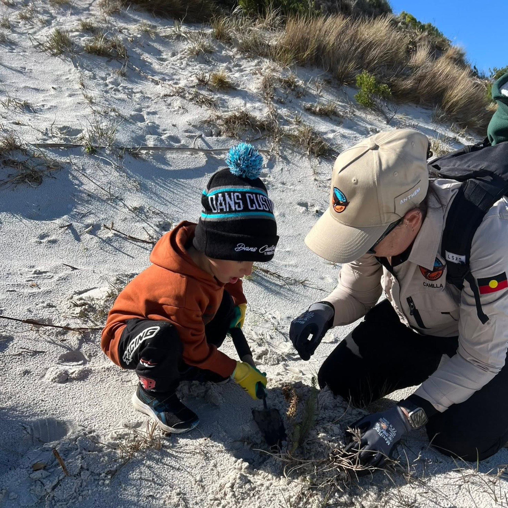 Tebrakunna Ranger and child removing sea spurge