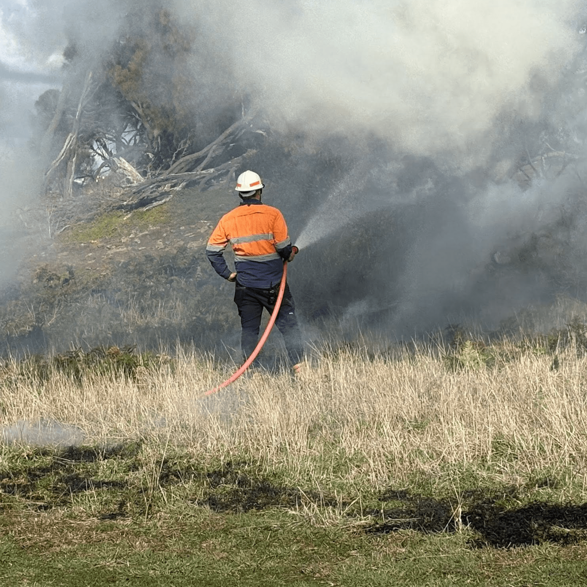 Aboriginal ranger with fire hose conducting cultural burning for land management